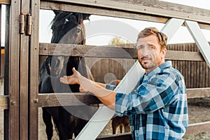 Rancher in shirt touching brown horse