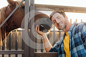 Rancher in shirt touching horse while