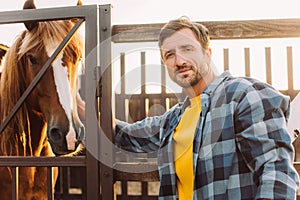 Rancher in shirt touching horse in