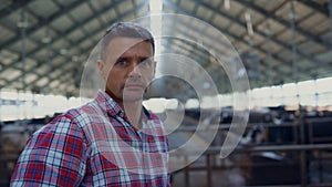 Rancher standing modern cowshed looking camera close up. Portrait farm employee.