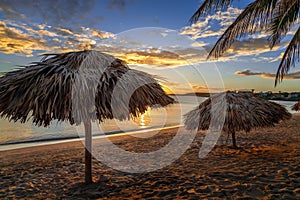 Rancho Luna caribbean beach with palms and straw umbrellas on the shore, sunset view, Cienfuegos, Cuba photo