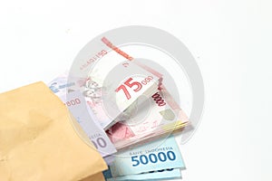 Random Layout Photo Rupiah Paper Money, 10000, 50000, 100000 and 75000 at Brown Envelope at White Background