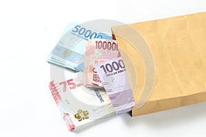 Random Layout Photo Rupiah Paper Money, 10000, 50000, 100000 and 75000 at Brown Envelope at White Background