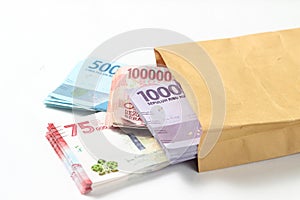 Random Layout Photo Rupiah Paper Money, 10000, 50000, 100000 and 75000 at Brown Envelope at White Background