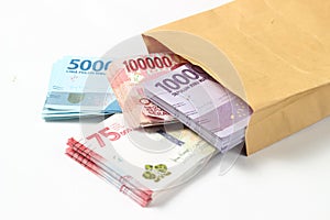Random Layout Photo Rupiah Paper Money, 10000, 50000, 100000 and 75000 at Brown Envelope at White Background
