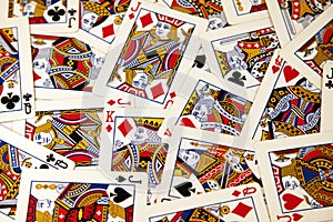 Random playing cards of kings, queens and jacks together forming a background