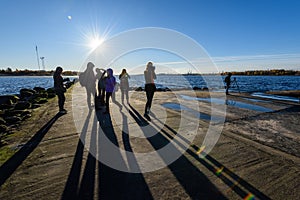 people enjoying sunset on the breakwater in the sea with lightho