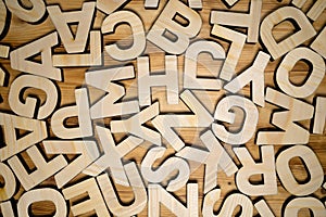 Random wooden block letters lying on wooden background. Top view