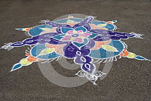 Rangoli handiwork design on floor with colored stone powder