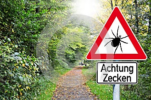 Raod sign in the forest with the german word for beware of ticks - Achtung Zecken