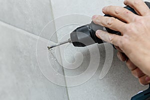 Rapairman drilling ceramic tile on a wall