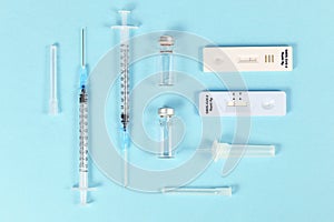 Rapid antigen test and vaccine vials with syringes. Tools to fight Corona Virus pandemic.