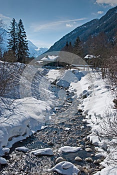 Rapid brook running by snowcapped banks