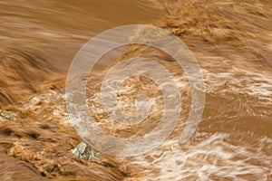 Rapid flow of brown water in the muddy river during rainy season