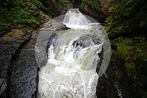 Rapid Rychenbachfall waterfall among stones and bushes near Meiringen, Switzerland