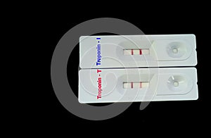 Rapid test device or cassette for Troponin I and Troponin T test showing positive result, black background with copy space.