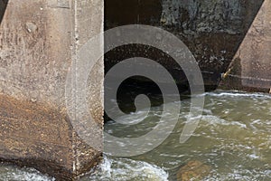 Rapidly moving water rushing around concrete bridge pilings