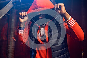 Rapper in red hoodie poses in grunge studio