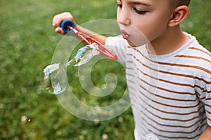 Rapt little boy blows bubbles in the park.