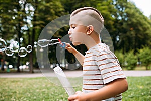 Rapt little boy blows bubbles in the park.