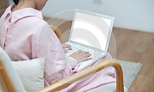 Rare or back view of young asian woman online using and looking hand typing at digital laptop with blank desktop screen sitting on