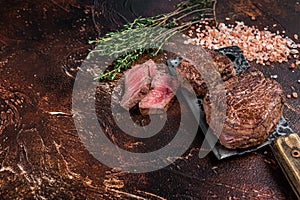 Rare Grilled fillet mignon beef steak on a meat cleaver. Dark background. Top view. Copy space