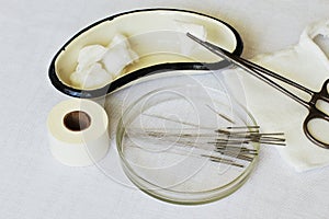 Rare medical supplies for acupuncture: metal kidney-shaped bath, packers with cotton swab, gauze mask, needles in Petri dish,