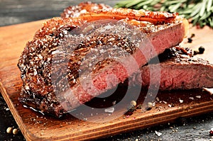 Rare New York strip steak on wooden board, selected focus