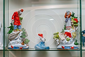 Rare porcelain figurines on a glass shelf. The Tale of the Fisherman and the Fish