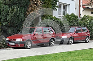 Two old classic small veteran Italian popular purple red cars Fiat Uno Fire 1.0 I.e.s parked