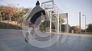 Rare view of a young girl basketball player training and exercising outdoors on the local court. Dribbling with the ball