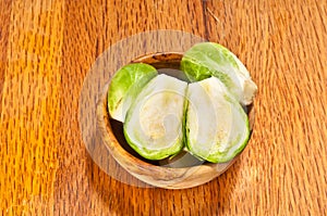 Rare wood bowl, filled with freshly picked Brussel sprouts with one cut in halve to reviel layered interio