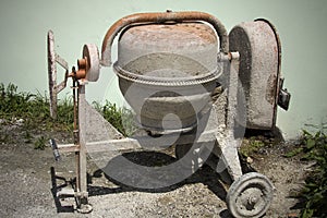 Rarely used Cement mixer standing near a wall. Cement mixers, or concrete mixers, allow users to mix large amount of cement, sand,