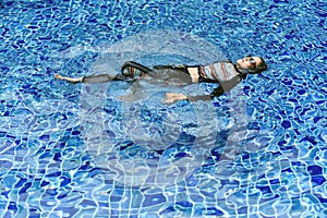 Rash guard swimming suit protect skin from uv sun ray, Woman floating in clear blue swimming pool.