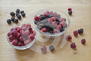 Raspberries and blackberries in a glass jar on a wooden table.