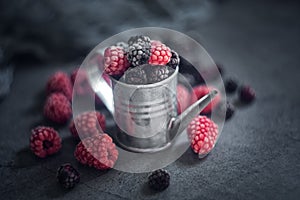 Raspberries and blackberries in a tin can