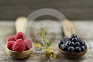 Raspberries and blueberries in spoons on wooden background. Healthy eating