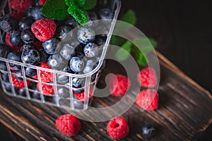 Raspberries and blueberry in a basket on a dark background. Summer and healthy food concept. Background with copy space