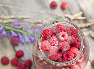 Raspberries in the glass over old aged wood table