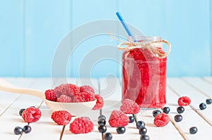 Raspberries jam in mason jar and fresh berries on