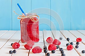 Raspberries jam in mason jar and fresh berries on