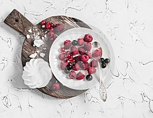 Raspberries, red and blackcurrants, a meringue on a rustic cutting board