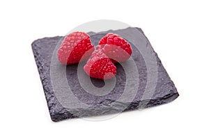 raspberries on slate on white background