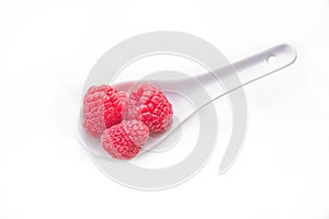 raspberries on spoon on white background from above