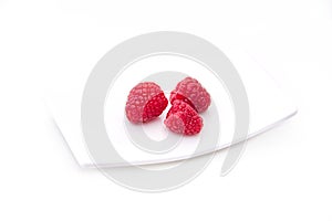 raspberries on tray on white background