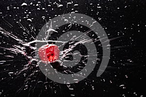 Raspberries in water splashes on a dark background