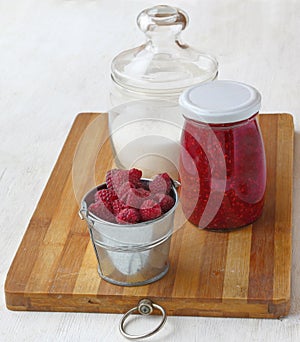 Raspberry on a background of of cans of jam and sugar