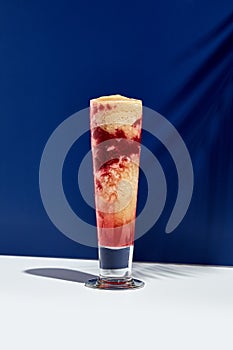 Raspberry and banana smoothie over white and blue background. Palm leaf with sunshine and hard shadow. Fruit yogurt or shake drink