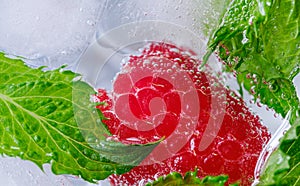 raspberry berry and green mint leaves in ice water closeup from top view