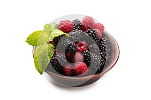 Raspberry, blackberry and mint leaf in ceramic brown bowl isolated on white